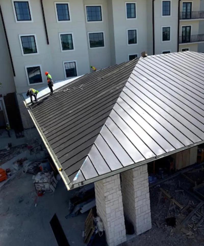 Crew installing standing seam metal roof panels on a commercial project in Egelston